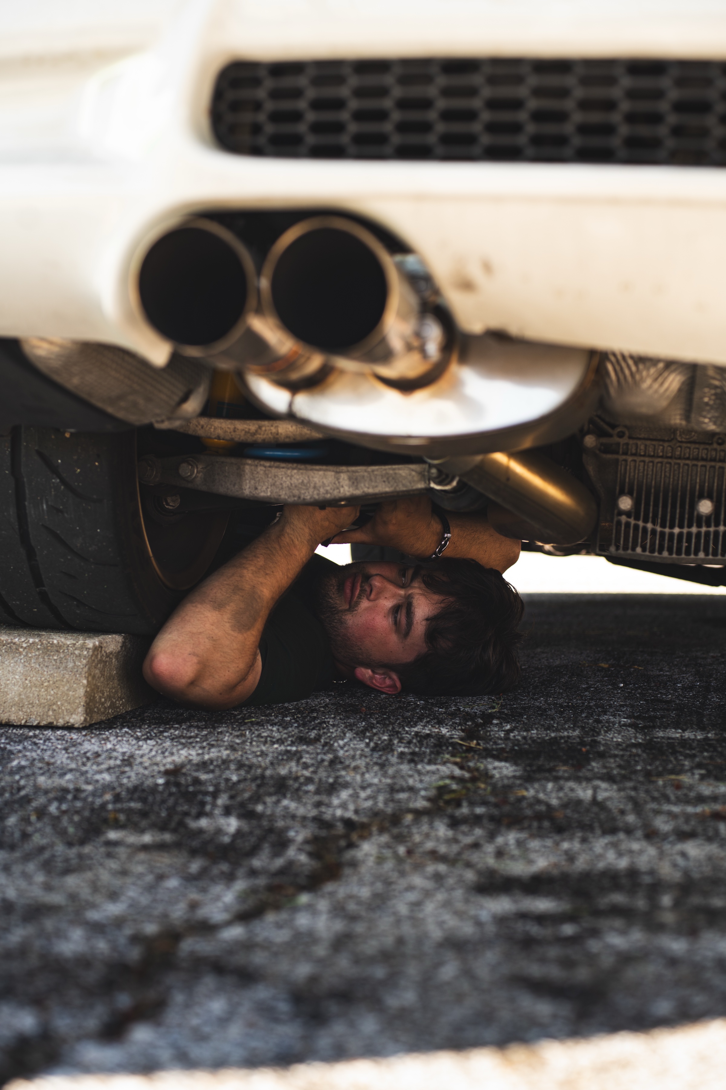 Will working underneath the rear of a white sports car